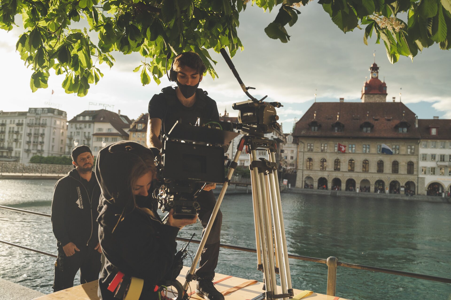 Film crew with cinema camera on tripod shooting in front of Lucerne old town and town hall