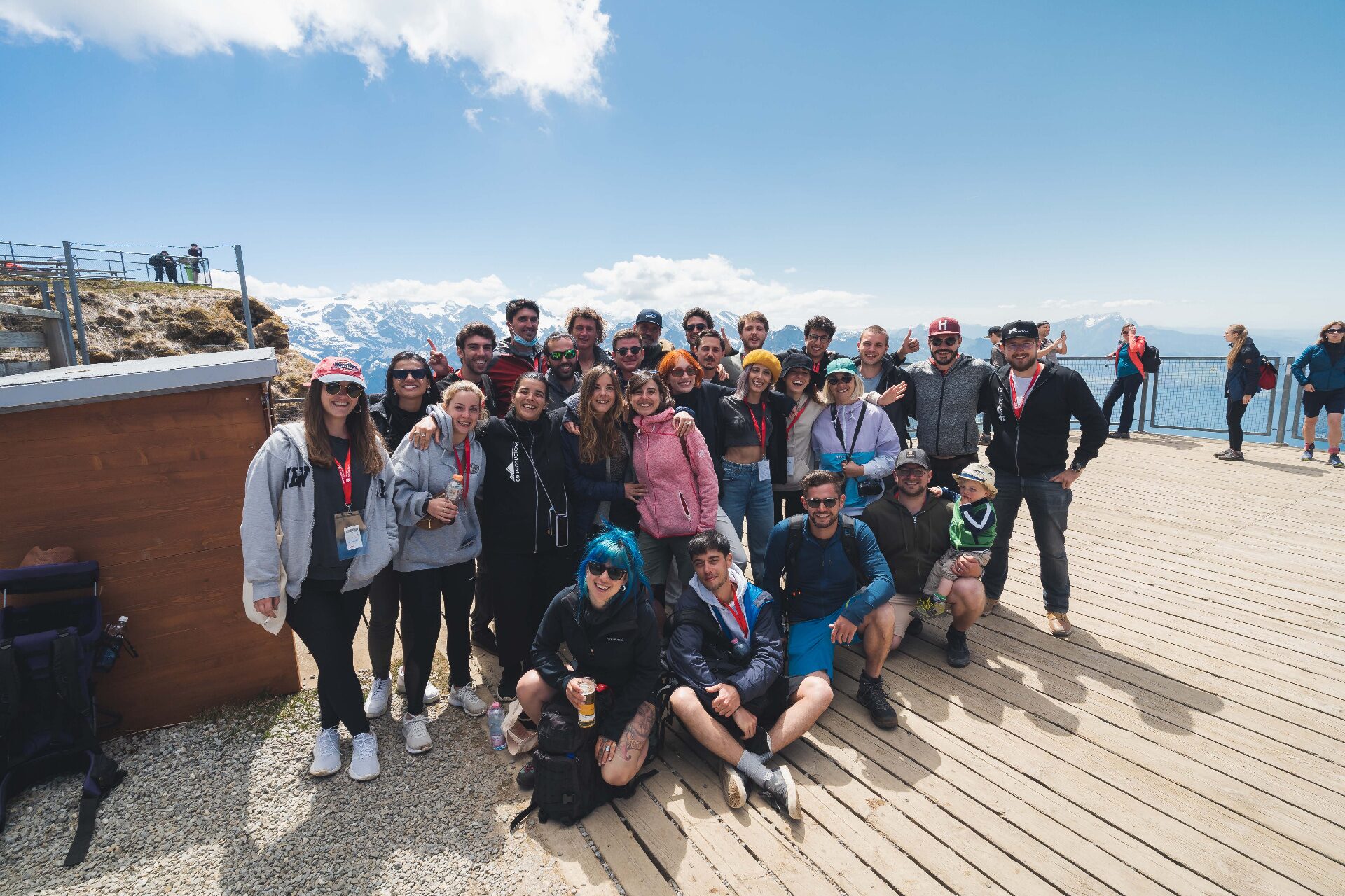 ORISONO crew group photo on a mountain platform above Swiss alpine lakes and snow peaks
