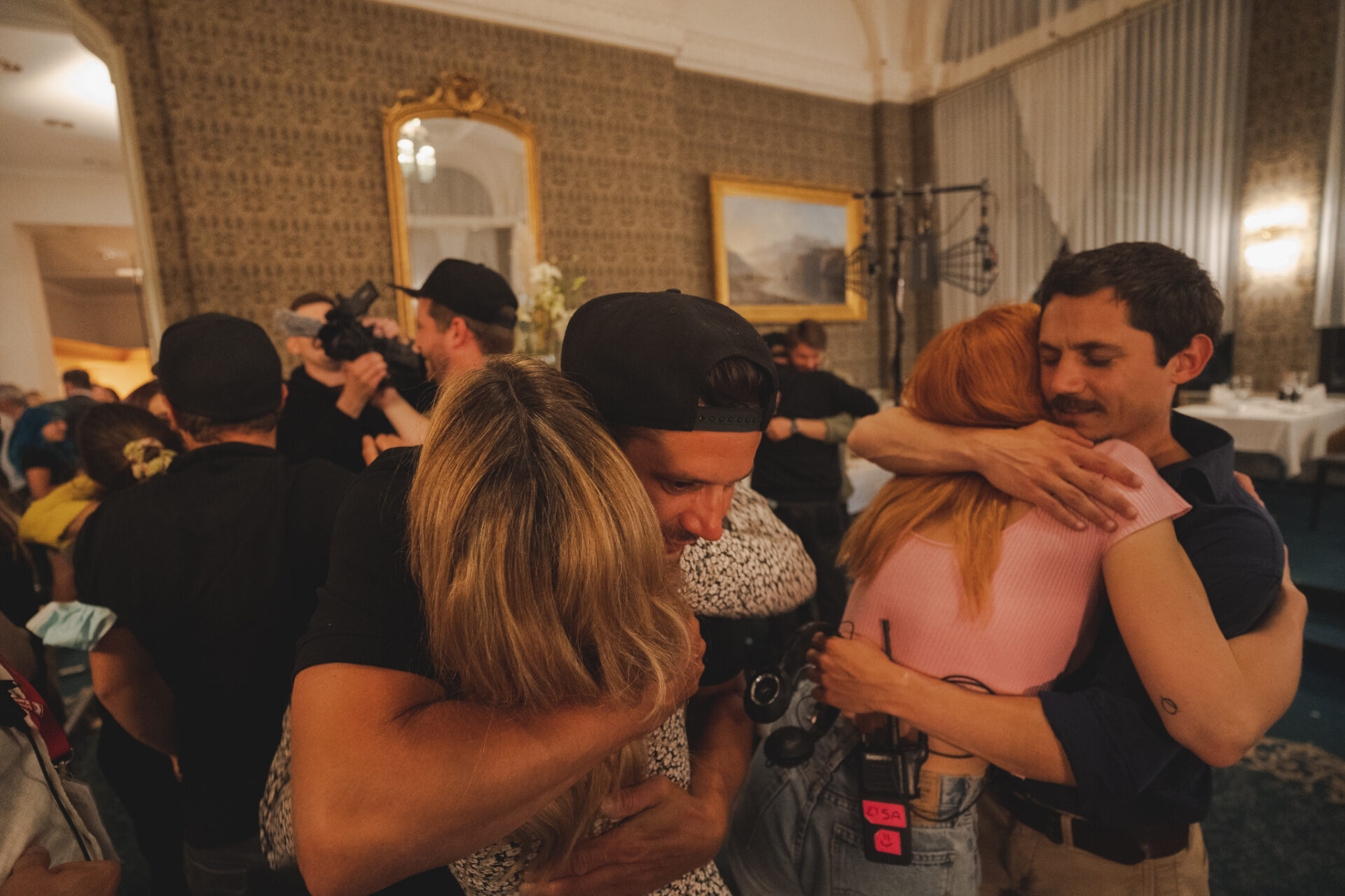 Crew and cast embrace at the production wrap inside a historic Swiss hotel salon