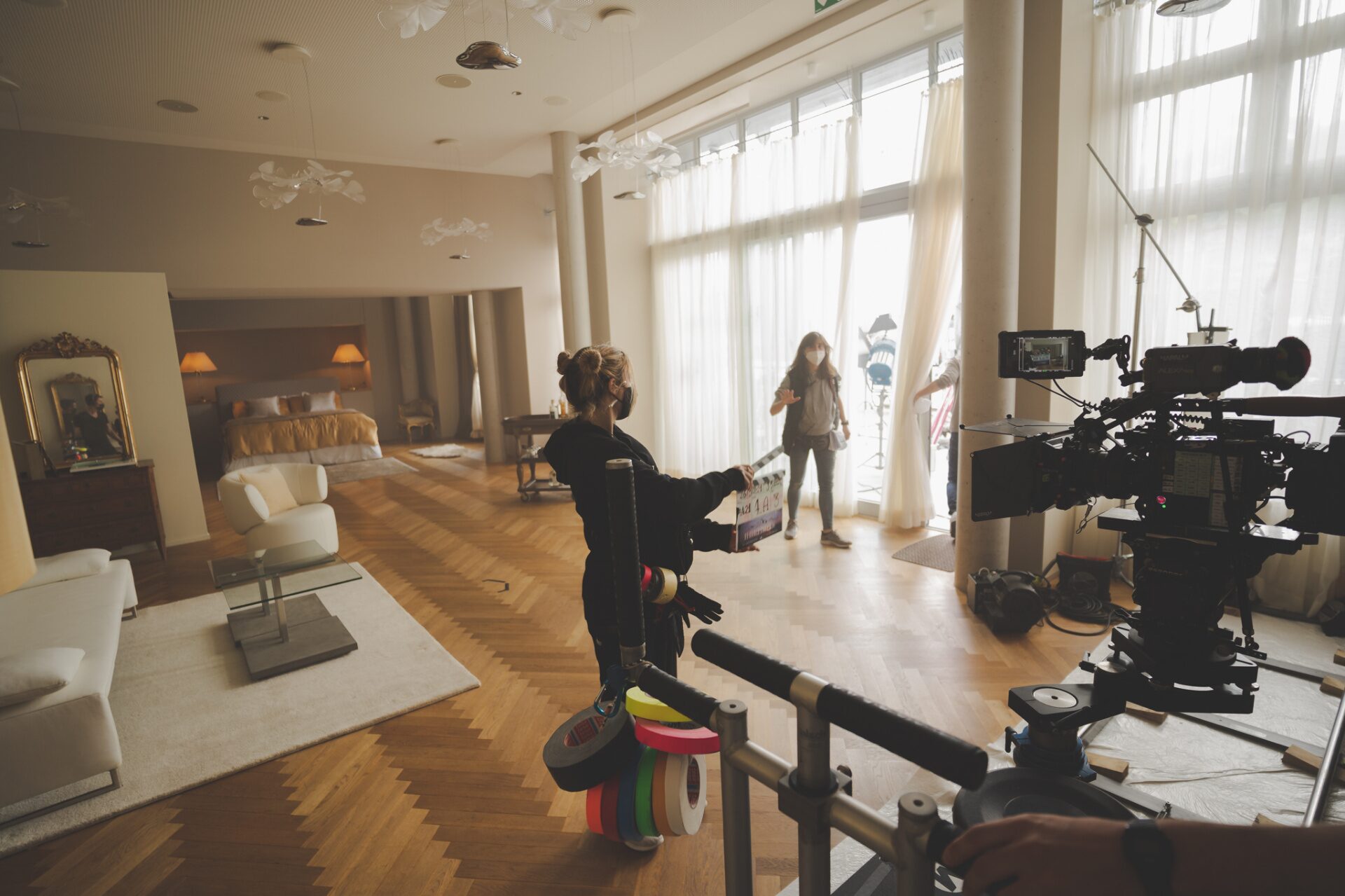 Slate operator marks a take inside a luxury hotel suite dressed as a film set