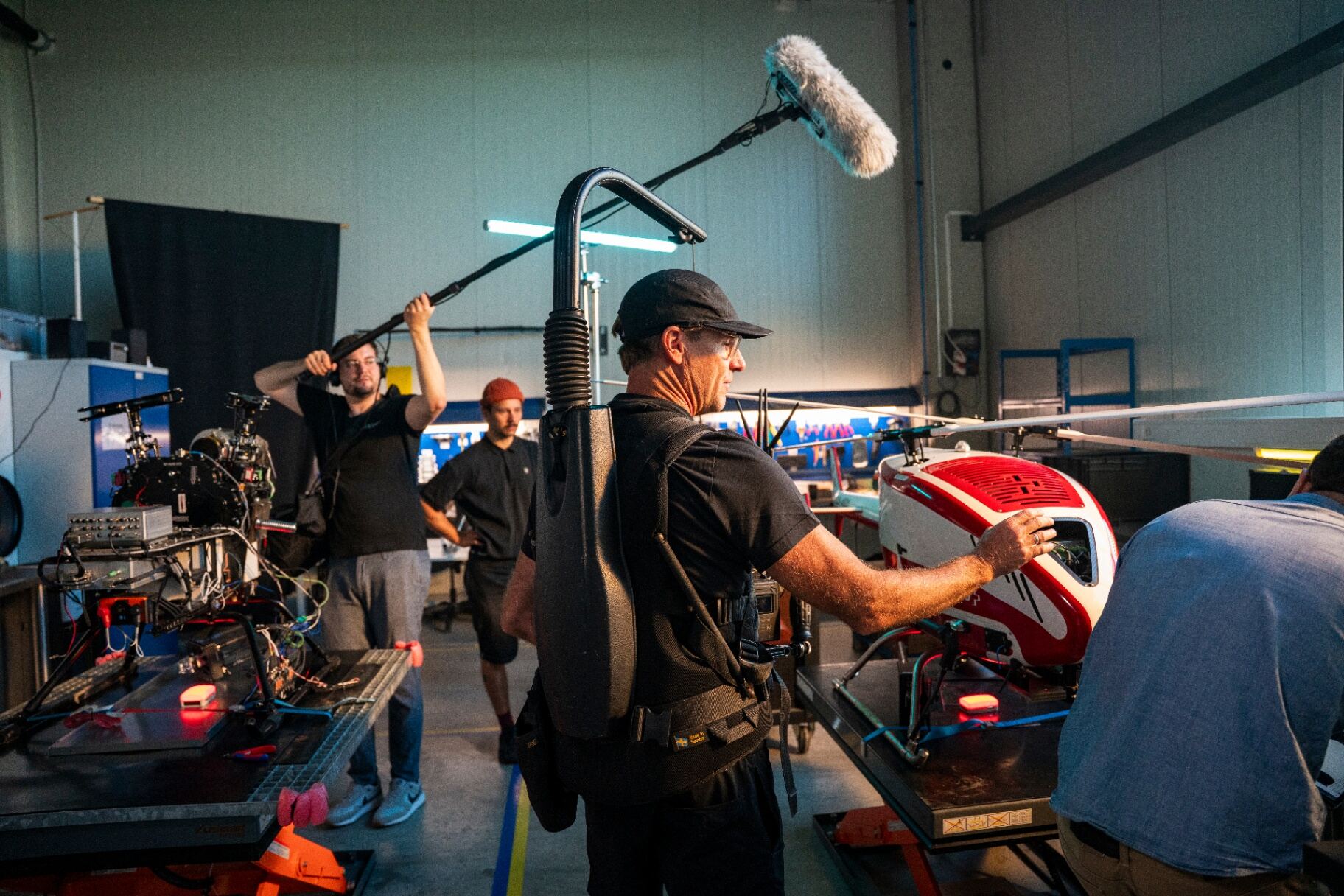 Steadicam operator and boom op shoot a red and white helicopter inside a Swiss hangar set