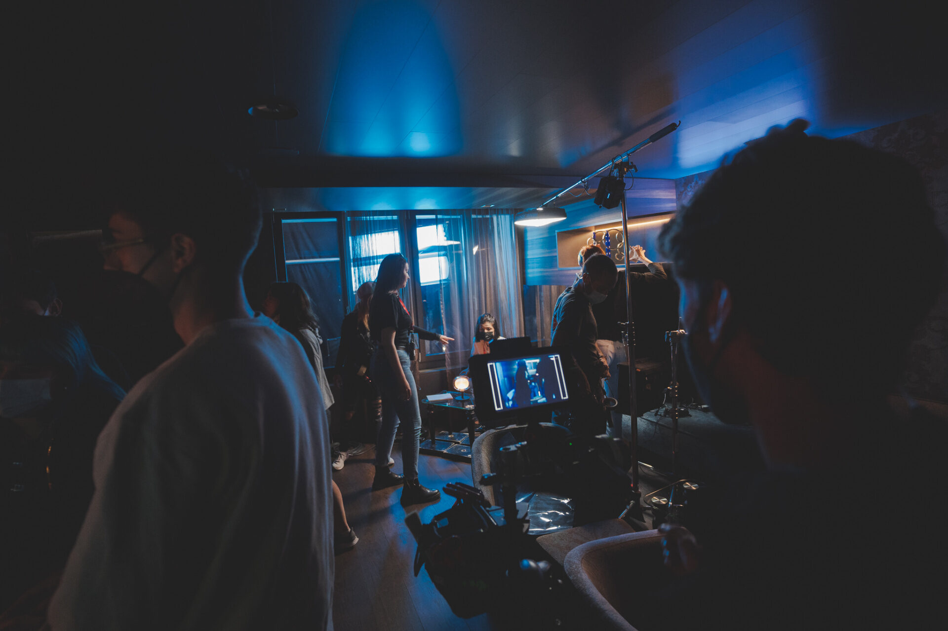 Night interior shoot with blue practical lighting, boom operator and director's monitor on set